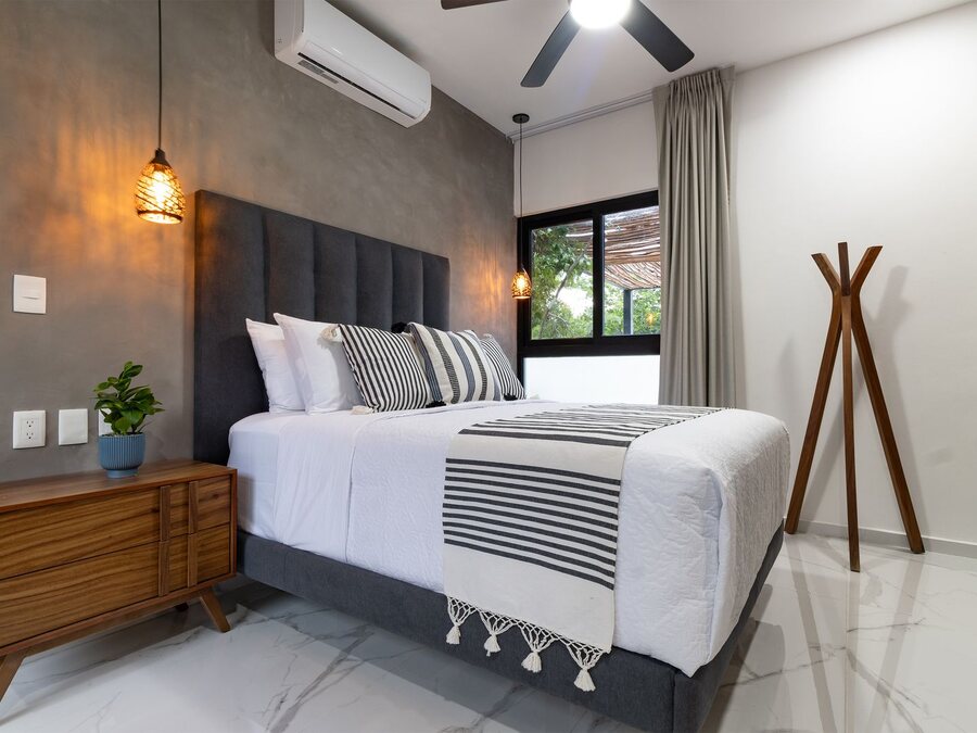 Minimalist bedroom with a soft neutral feature wall and restrained, uncluttered styling.