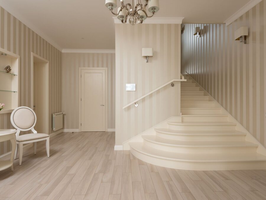 Elegant entry hall with a subtly striped tonal neutral wall covering and a curved staircase.